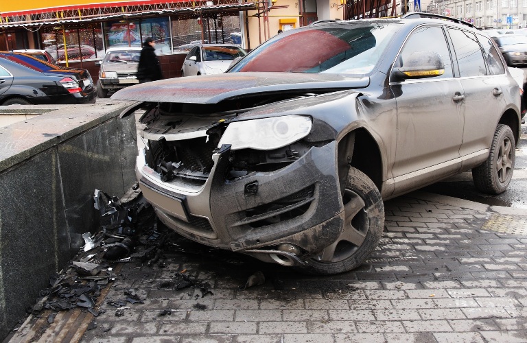 crashed car stands on a sidewalk
