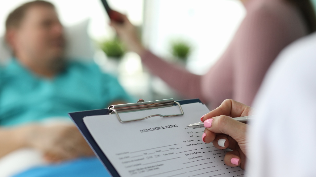 Female doctor fills in patient medical record
